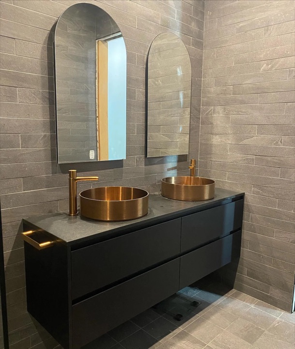 Dark floating cabinets beneath two illuminated mirrors