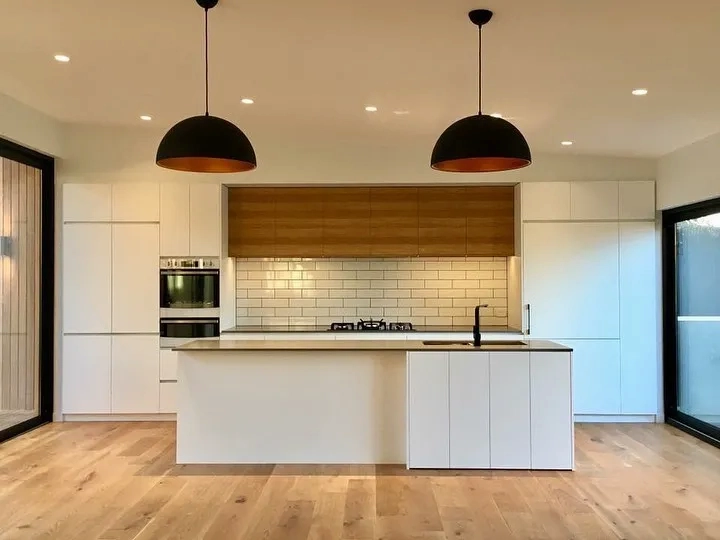 White kitchen with timber overheads and pendant lighting in a home extension