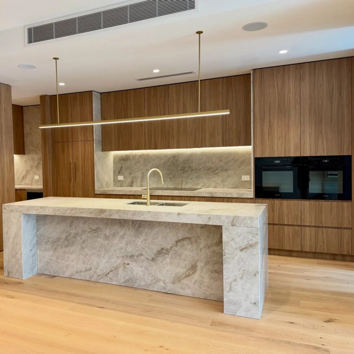 Brown-grained cabinets and a pale veined island