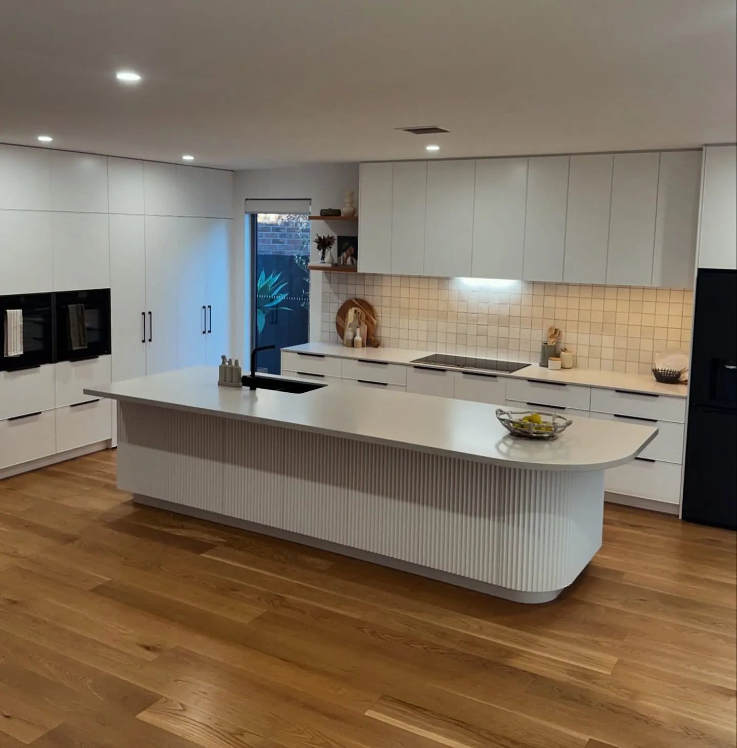 White cabinetry surrounding a long island with a ribbed curved end