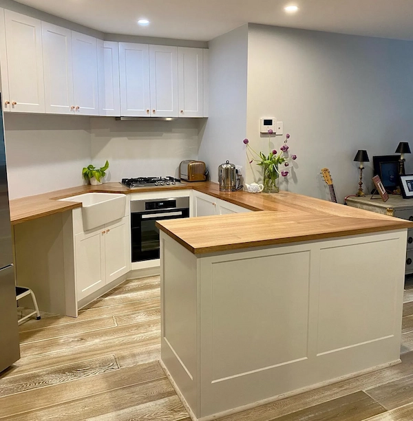 White shaker kitchen with solid timber benchtop and a farmhouse-style sink