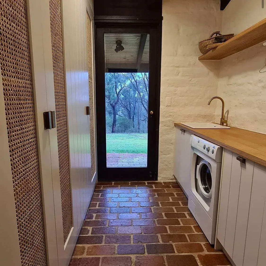 White cabinetry with woven door panels beside a timber work surface and floating shelf