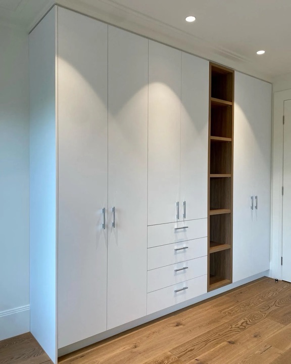 Tall pale built-in doors beside open brown-grained shelves