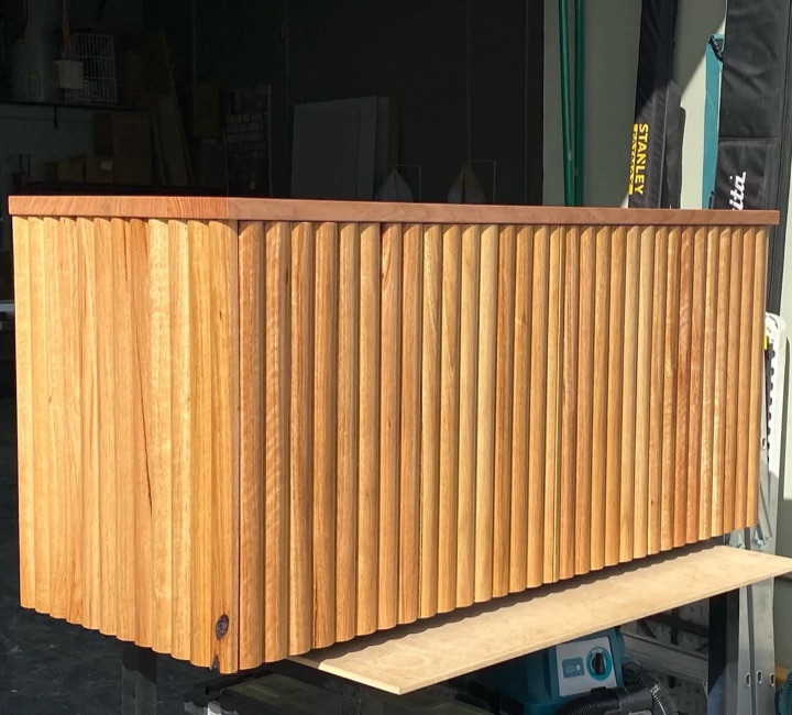A freestanding cabinet with closely spaced vertical timber slats