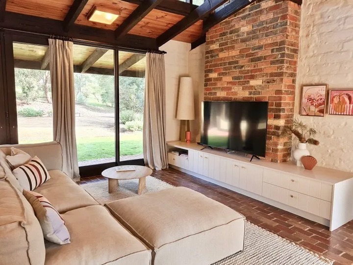 Low white cabinets beneath a television against a red patterned wall