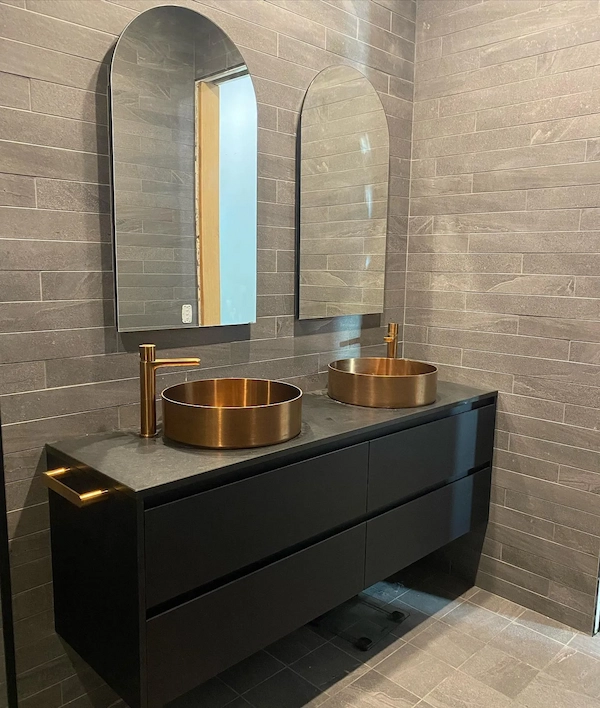 Matte black double vanity with bronze basins and arched mirrors